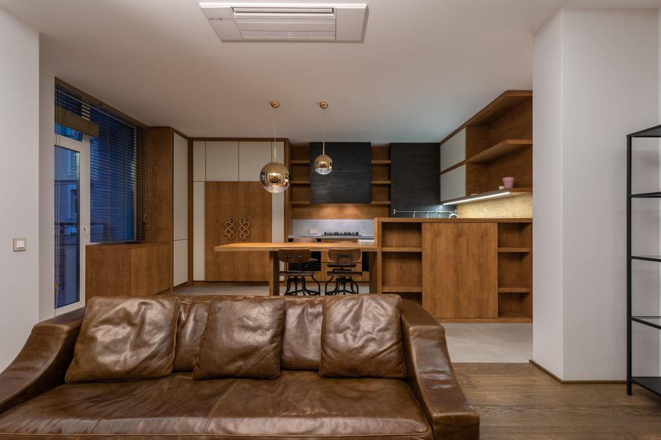Comfortable leather sofa with pillows in contemporary apartment with modern interior and shelves